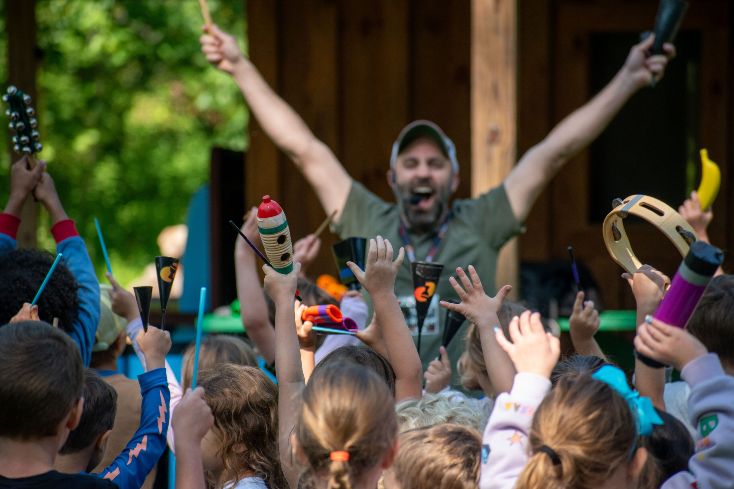 Matt Price from DrumNexus with hands in air leading a group of kids playing percussion instruments.