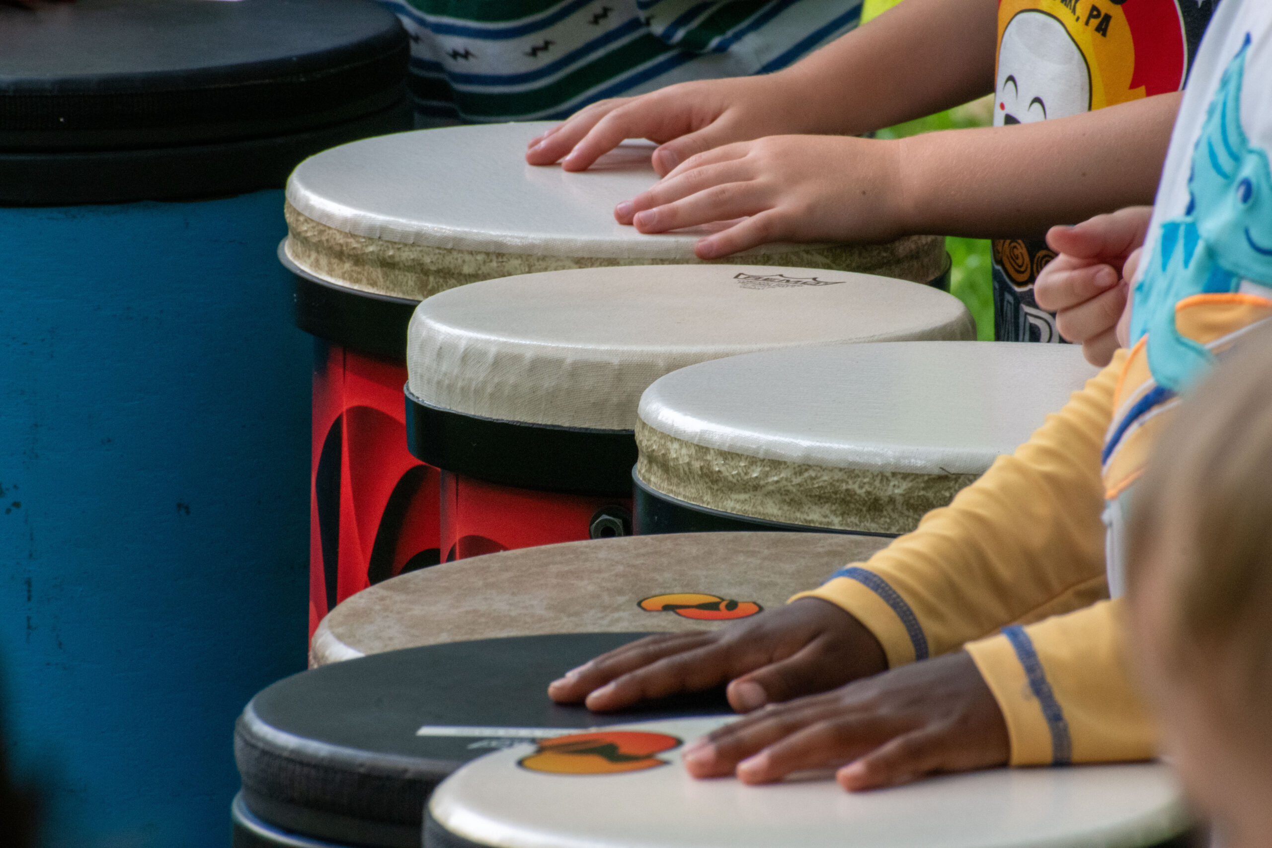Young kids play hand drums at a drum circle lead by DrumNexus at Camp Deer Creek